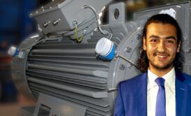 A suited man stands next to a large electric motor, emphasizing the role of electrical machines in modern technology.