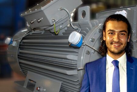 A suited man stands next to a large electric motor, emphasizing the role of electrical machines in modern technology.