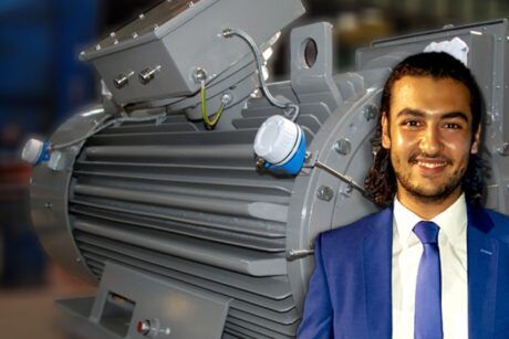 A suited man stands next to a large electric motor, emphasizing the role of electrical machines in modern technology.