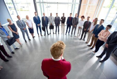 a group of business professionals standing in a circle, engaged in a discussion about how to be a leader
