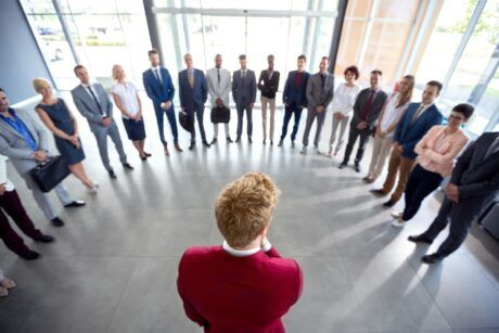 a group of business professionals standing in a circle, engaged in a discussion about how to be a leader