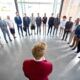 a group of business professionals standing in a circle, engaged in a discussion about how to be a leader
