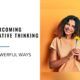 a woman smiling while holding a flower, symbolizing how to overcome negative thinking