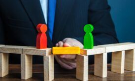 a man in a suit holds wooden blocks depicting people, illustrating the concept of how to set healthy boundaries