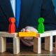 a man in a suit holds wooden blocks depicting people, illustrating the concept of how to set healthy boundaries