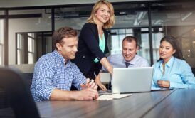 a group of people collaborating around a table with a laptop, focused on enhancing meeting productivity
