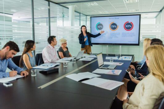 a woman presents a powerpoint to an audience, demonstrating effective presentation skills powerpoint