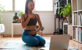 a woman seated on the floor with her laptop, embodying the art of meditation in a calm and peaceful setting