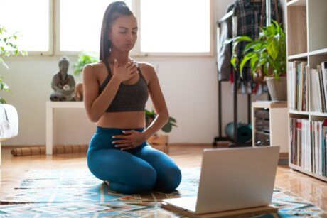 a woman seated on the floor with her laptop, embodying the art of meditation in a calm and peaceful setting