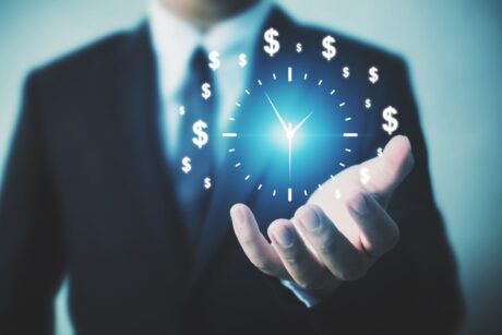 businessman holding a clock adorned with dollar signs, symbolizing time management hacks for financial success