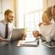 Three people gathered around a table with a laptop, focused on understanding life insurance basics.
