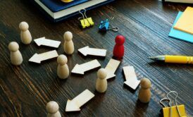 a wooden board featuring wooden figures and arrows, illustrating delegation training for managers