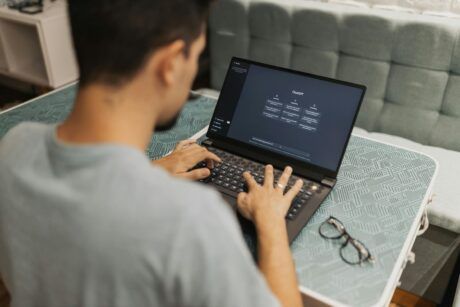 a man focused on his laptop, typing prompt engineering with chatgpt in a workspace setting