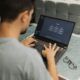 a man focused on his laptop, typing prompt engineering with chatgpt in a workspace setting