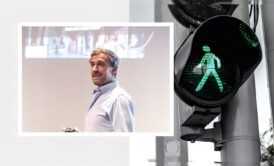 a man stands beside a traffic light and a green pedestrian sign, symbolizing sales closing techniques