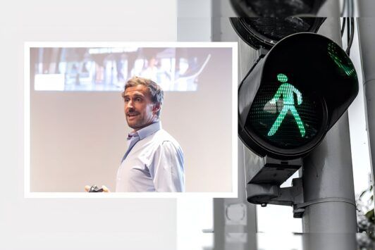 a man stands beside a traffic light and a green pedestrian sign, symbolizing sales closing techniques