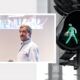 a man stands beside a traffic light and a green pedestrian sign, symbolizing sales closing techniques