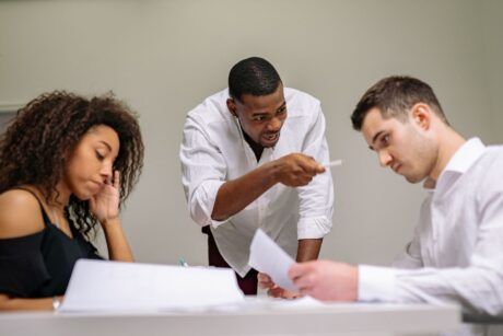 a man points at a woman and another man during a stress management class meeting