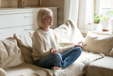 a woman practicing mindfulness meditation on a couch during a mindfulness course