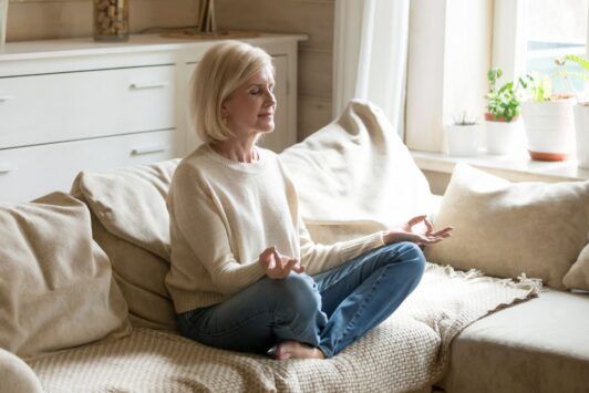 a woman practicing mindfulness meditation on a couch during a mindfulness course