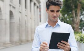 a man in a blue shirt holds a tablet, likely studying for an ACCA course
