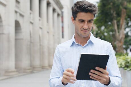 a man in a blue shirt holds a tablet, likely studying for an ACCA course