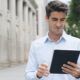 a man in a blue shirt holds a tablet, likely studying for an ACCA course