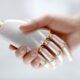 a robot hand and a human hand engaged in a handshake, symbolizing collaboration between technology and humanity