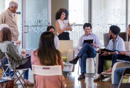 a group of people seated in chairs during a facilitation course in a meeting room