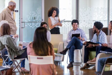 a group of people seated in chairs during a facilitation course in a meeting room