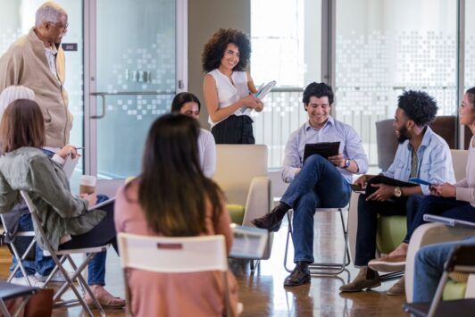 a group of people seated in chairs during a facilitation course in a meeting room