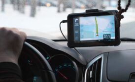 a person driving a car with a GPS device on the dashboard, indicating location targeting for navigation
