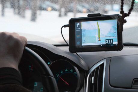 a person driving a car with a GPS device on the dashboard, indicating location targeting for navigation