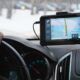 a person driving a car with a GPS device on the dashboard, indicating location targeting for navigation