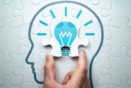 a hand holds a puzzle piece shaped like a light bulb, symbolizing problem solving training and creative thinking
