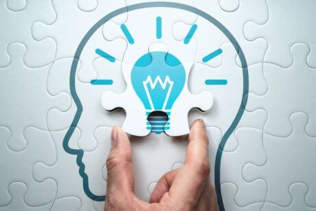 a hand holds a puzzle piece shaped like a light bulb, symbolizing problem solving training and creative thinking
