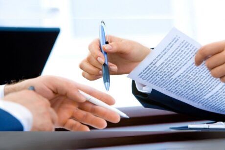 two business professionals shaking hands over contract papers, symbolizing agreement in a contract management course