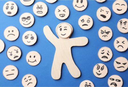 a wooden figure stands before a group of wooden figures displaying various emotions, symbolizing emotional intelligence training online