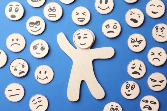 a wooden figure stands before a group of wooden figures displaying various emotions, symbolizing emotional intelligence training online