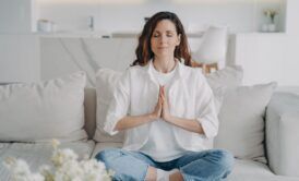 a woman sitting cross-legged on a couch, meditating to promote how to change your mindset