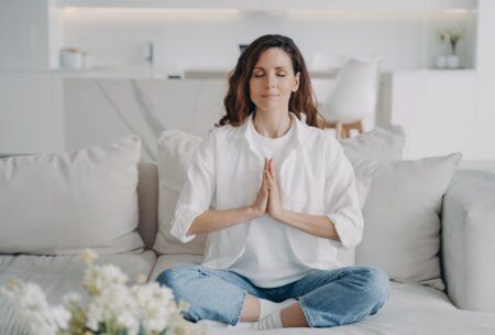 a woman sitting cross-legged on a couch, meditating to promote how to change your mindset